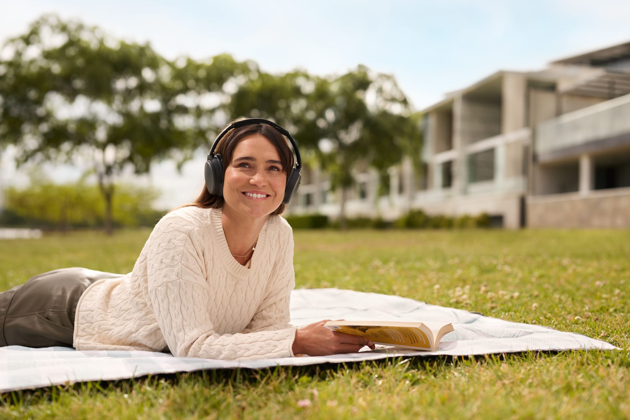 Person relaxing in park listening to music and reading book